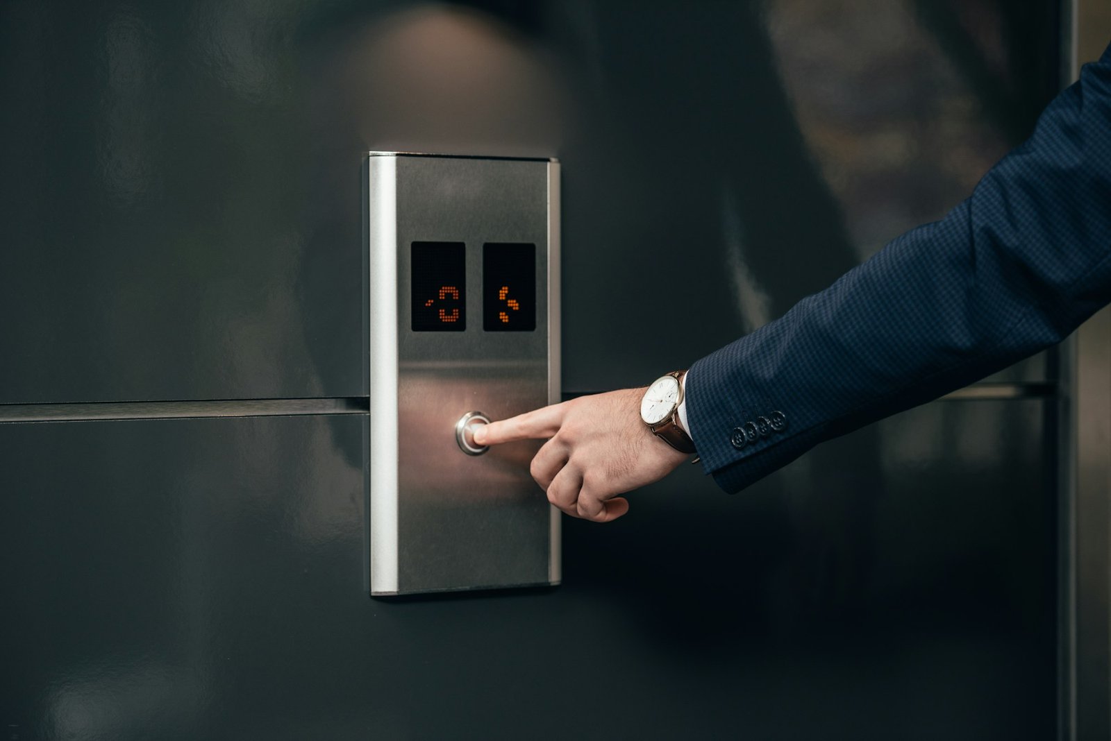 cropped shot of businessman in suit pressing button of elevator